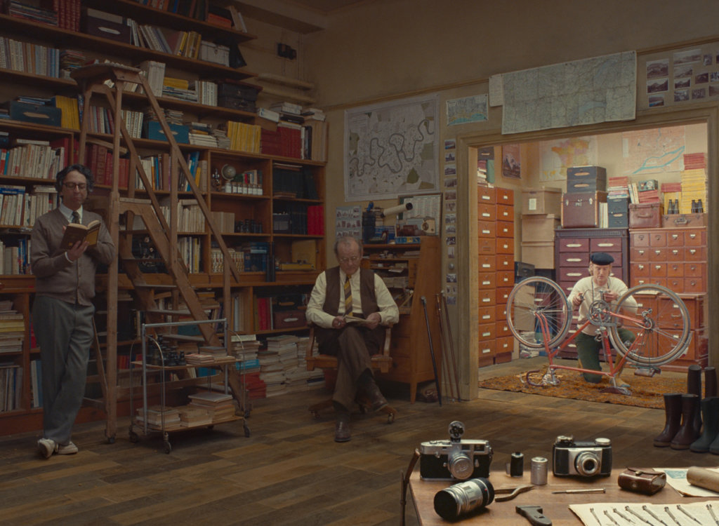 Still frame from The French Dispatch of characters sitting in a library