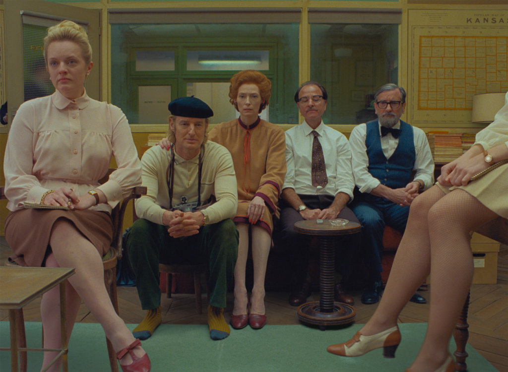 Still frame from The French Dispatch-characters listening attentively in meeting